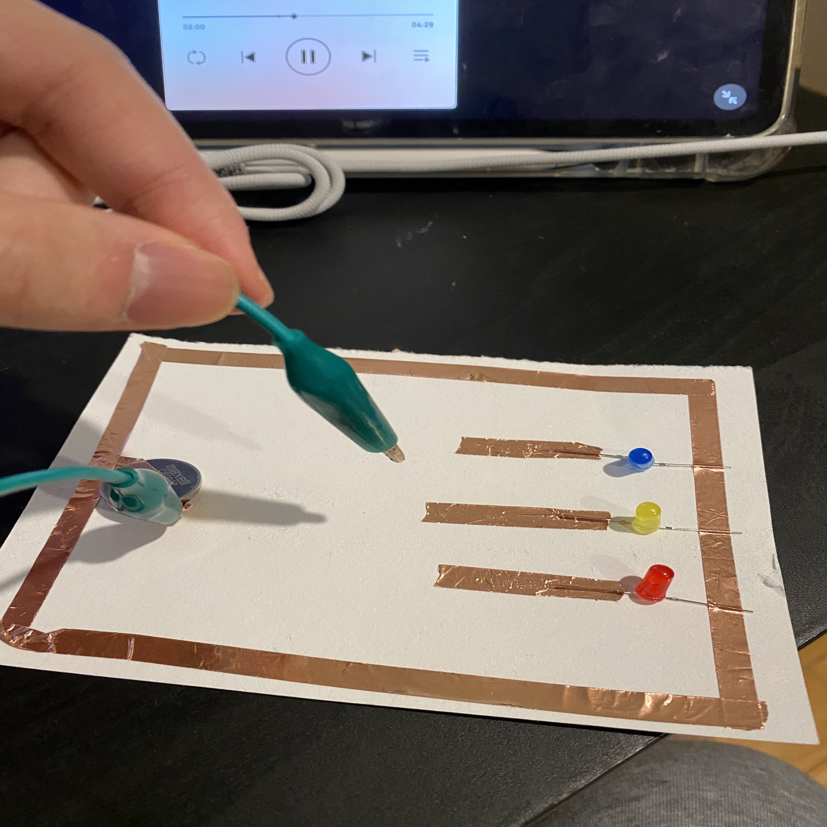 A circuit that allows the user to select one of the three LED lights to light up by touching the wires.