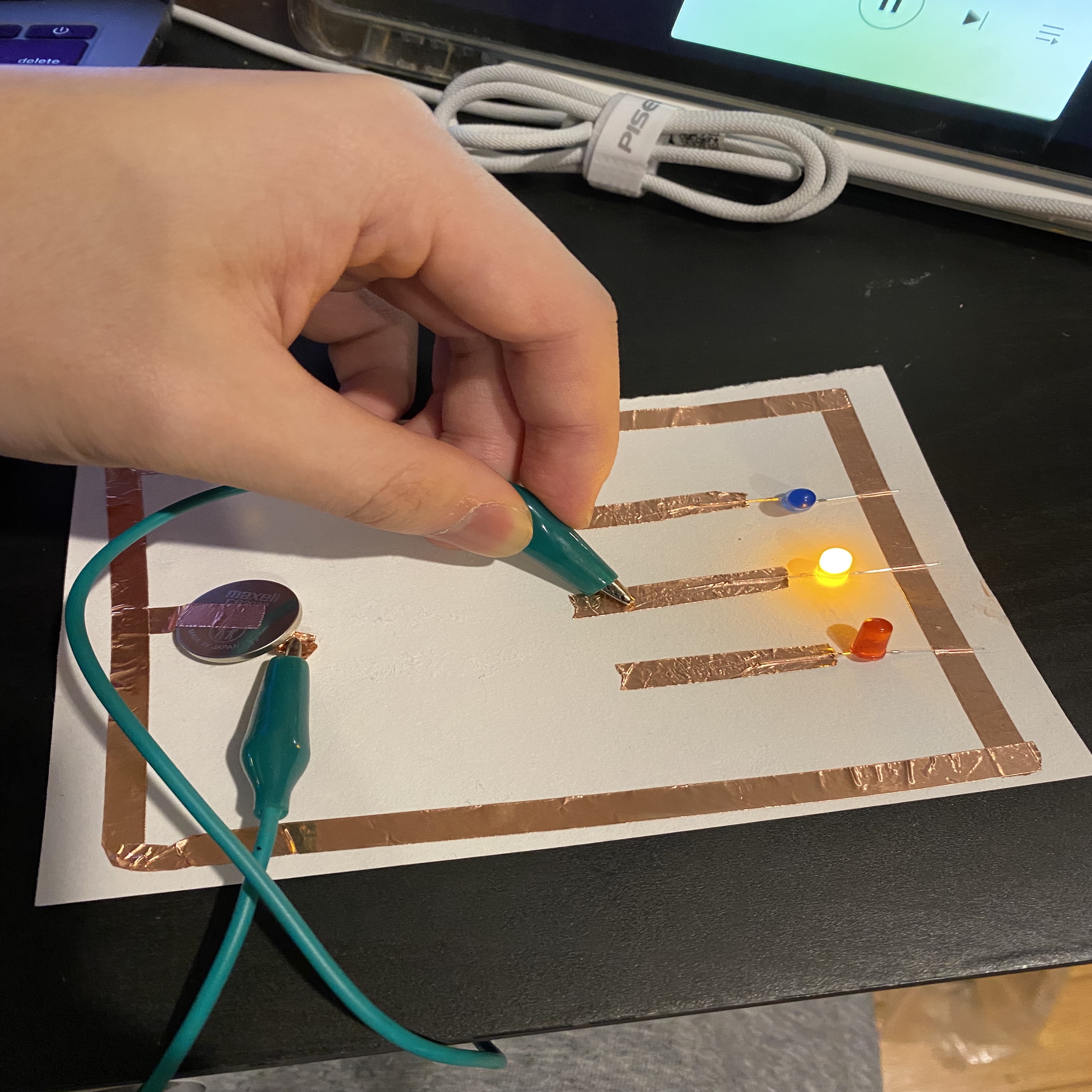 A circuit that allows the user to select one of the three LED lights to light up by touching the wires.(yellow on)