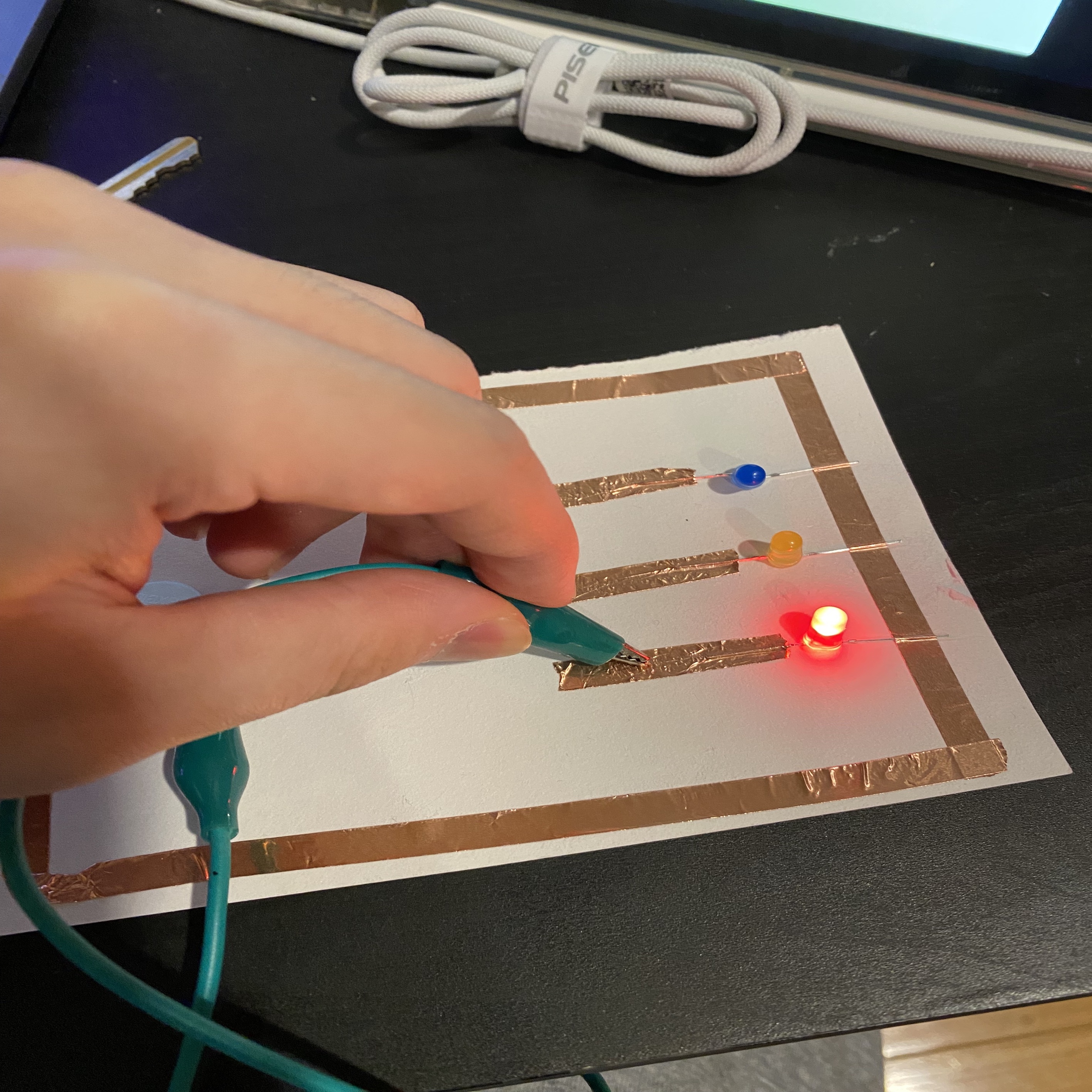 A circuit that allows the user to select one of the three LED lights to light up by touching the wires.(red on)